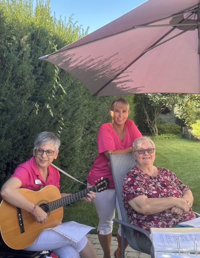 Drei Damen im Bild, eine mit Gitarre